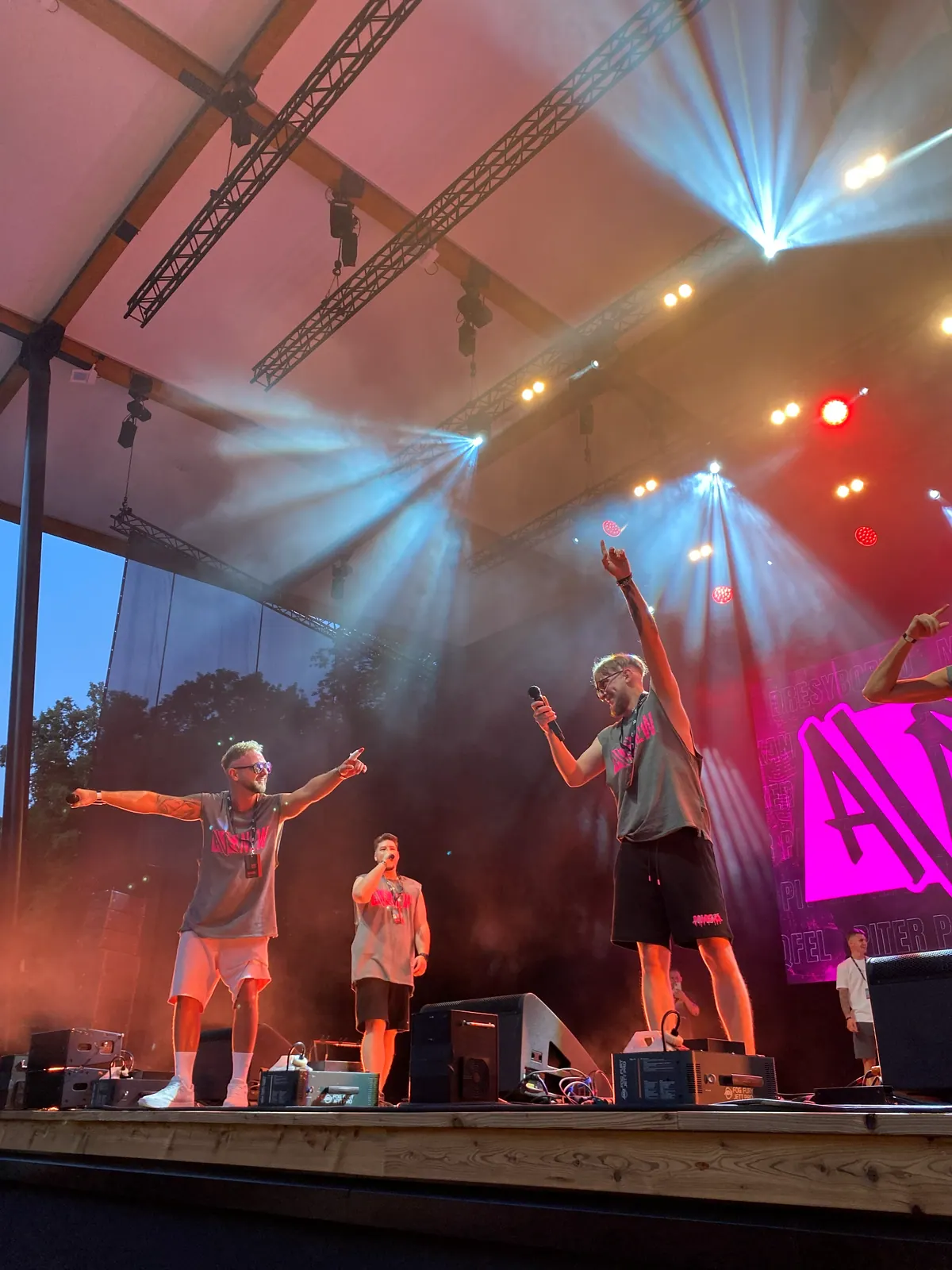 AVENEW z rozłożonymi rękami na scenie, w dymie i świetle reflektorów